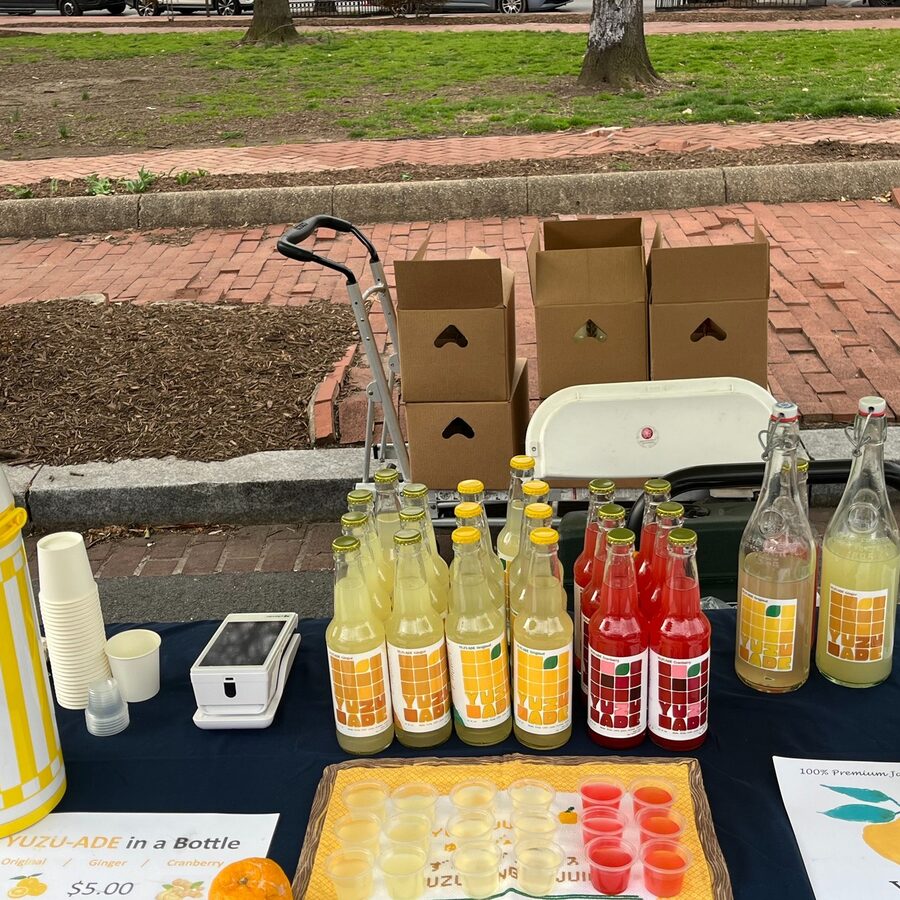 YUUZ farmers market table with Original, Ginger, and Cranberry bottles